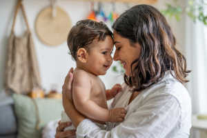 A mother gently cuddling her smiling baby indoors in a warm, natural setting, evoking comfort and care during a teething fever.